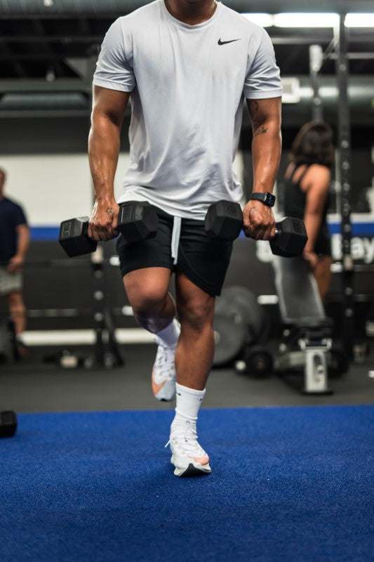 Hombre levantando pesas en gimnasio después de tomar aminoácidos
