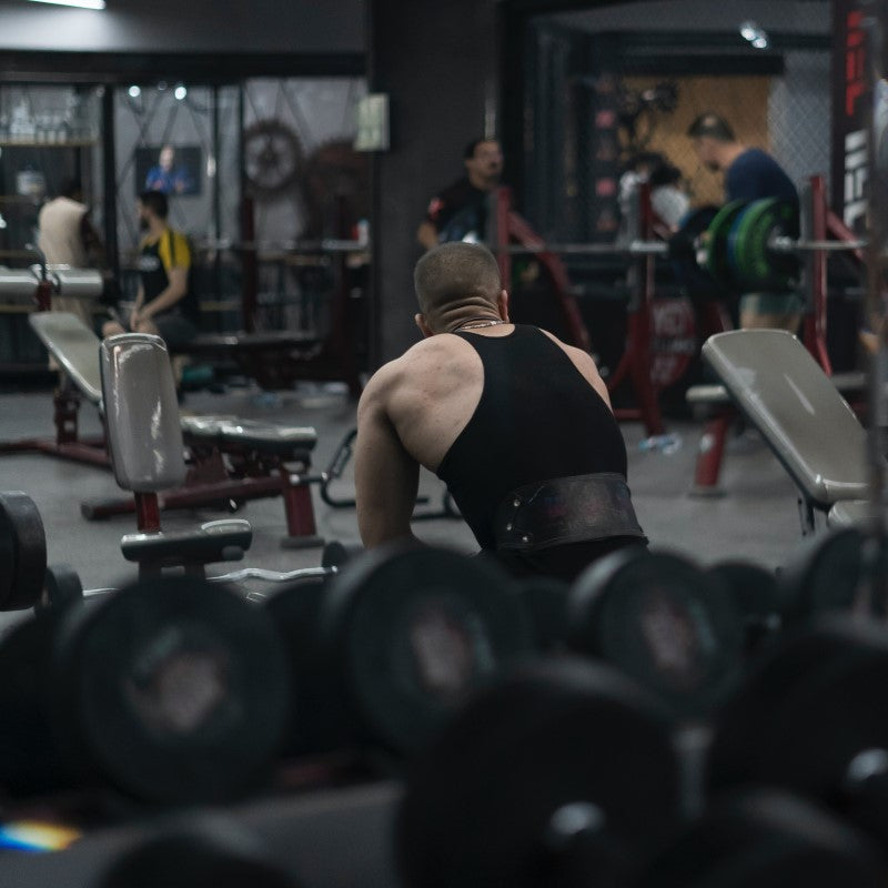 Hombre lleva cinturón de gimnasio para evitar lesiones durante el levantamiento de peso