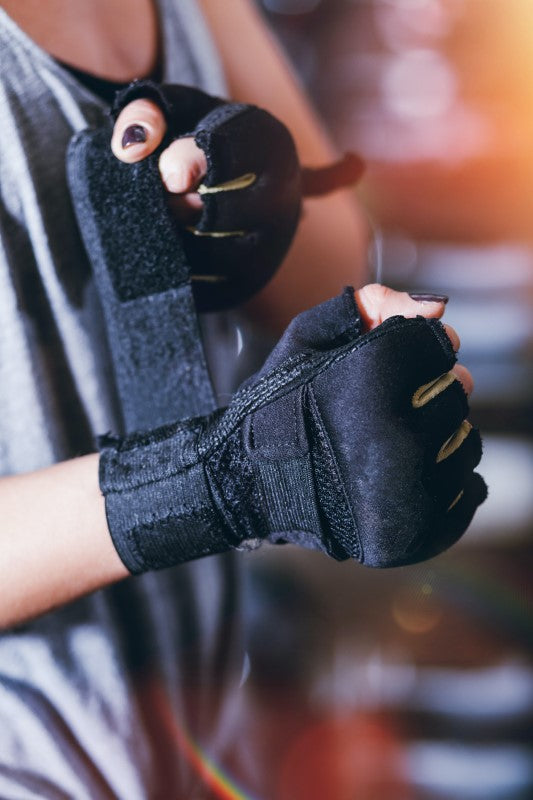 Mujer poniendose guantes de entrenamiento de color negro