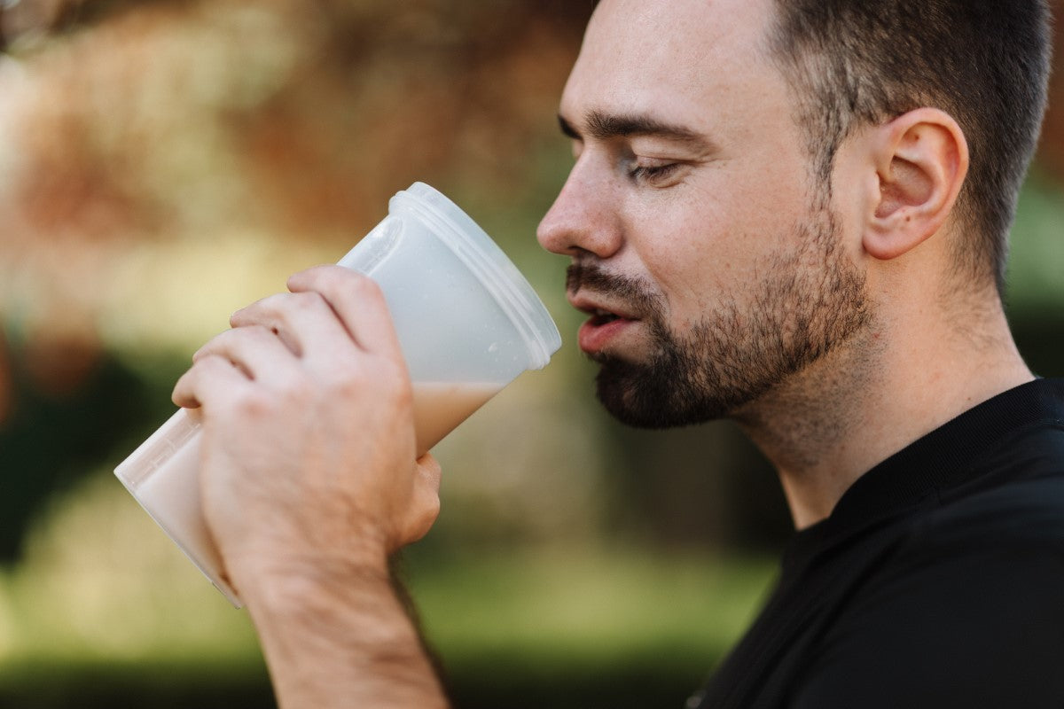 Hombre bebiendo batido de proteínas de vaso mezclador